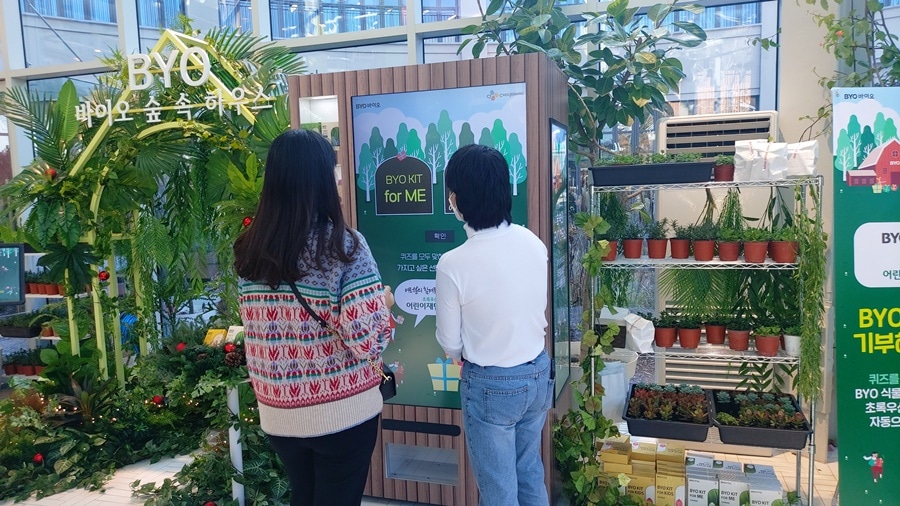 기부를 대신 해주는 자판기. 퀴즈를 맞추면 CJ제일제당 식물성 유산균 BYO바이오를 초록우산 어린이재단에 대신 기부해 주는 스마트벤딩머신. 행사에는 프로스크(프로모션 키오스크)